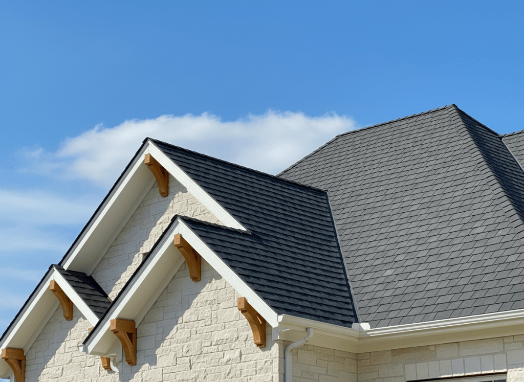 Upscale residential roof with charcoal shingles, white trim and stone exterior